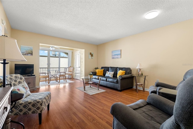 living room with wood finished floors, baseboards, and a textured ceiling