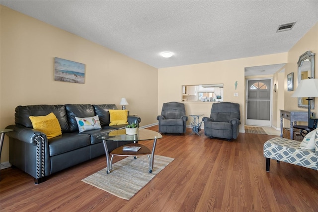 living area with baseboards, wood finished floors, visible vents, and a textured ceiling