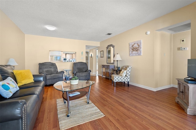 living area featuring visible vents, baseboards, a textured ceiling, and wood finished floors