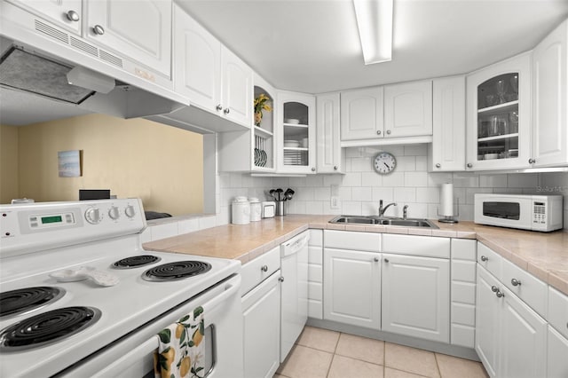 kitchen featuring under cabinet range hood, backsplash, white appliances, and a sink