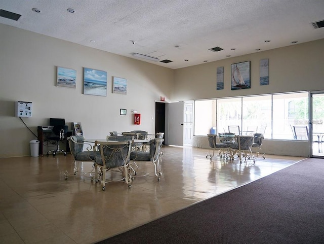 dining room with visible vents, a towering ceiling, and a textured ceiling