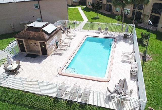 pool featuring a yard, a patio, and fence