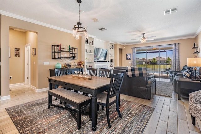 dining area featuring light wood finished floors, visible vents, a textured ceiling, and crown molding