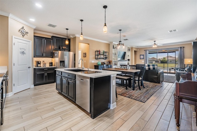 kitchen with wood finish floors, open floor plan, light countertops, appliances with stainless steel finishes, and a sink