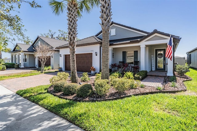 view of front of house with a garage, decorative driveway, covered porch, and stucco siding