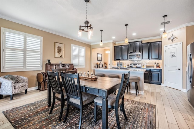 dining room featuring light wood-type flooring, visible vents, arched walkways, and crown molding