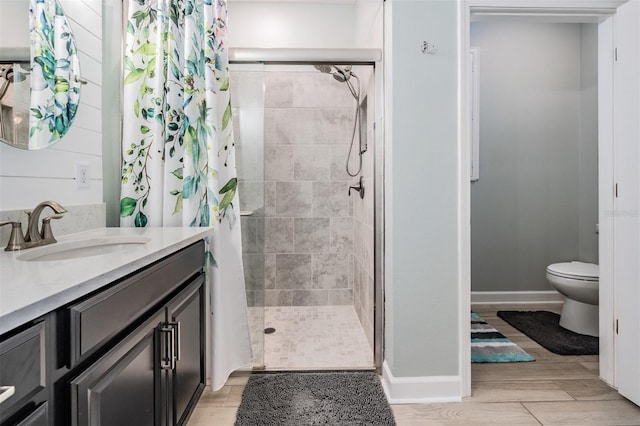 bathroom with baseboards, toilet, a stall shower, wood finished floors, and vanity