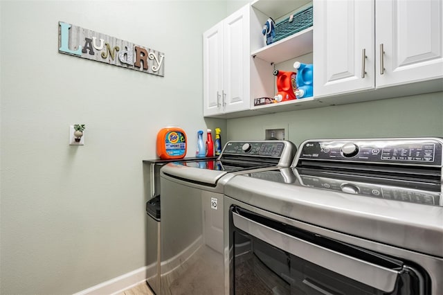 washroom featuring cabinet space, washer and dryer, and baseboards