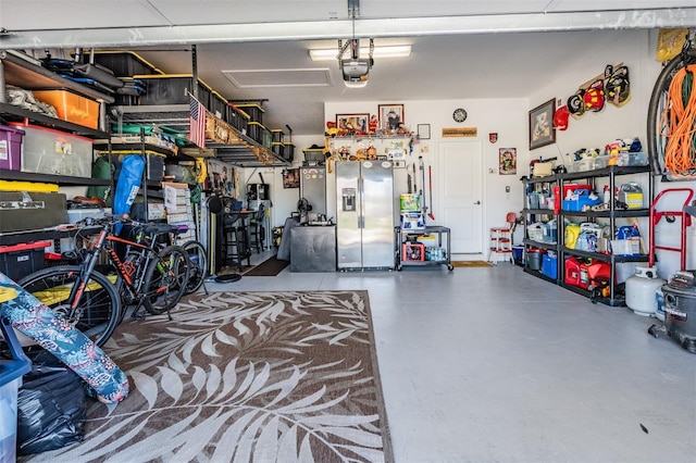 garage with a garage door opener and stainless steel refrigerator with ice dispenser