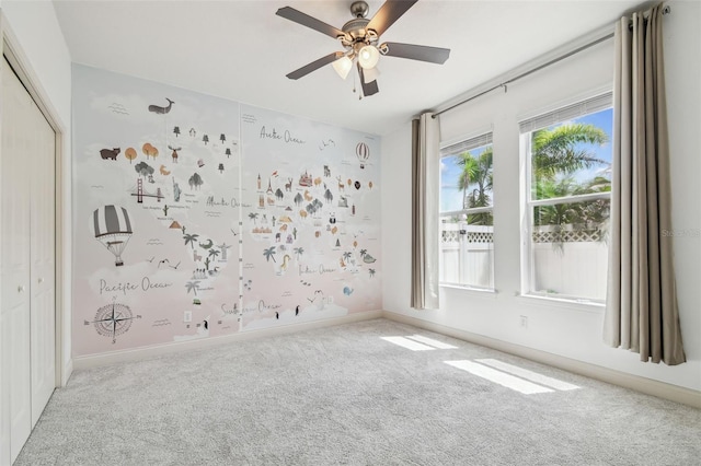 empty room featuring carpet floors, a ceiling fan, and baseboards