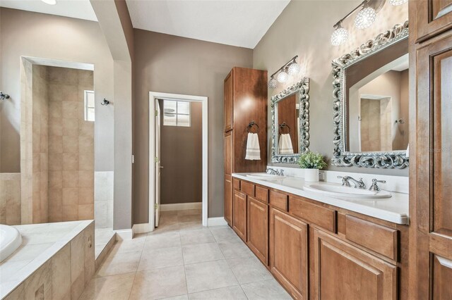 bathroom with tile patterned flooring, tiled tub, a sink, and a tile shower