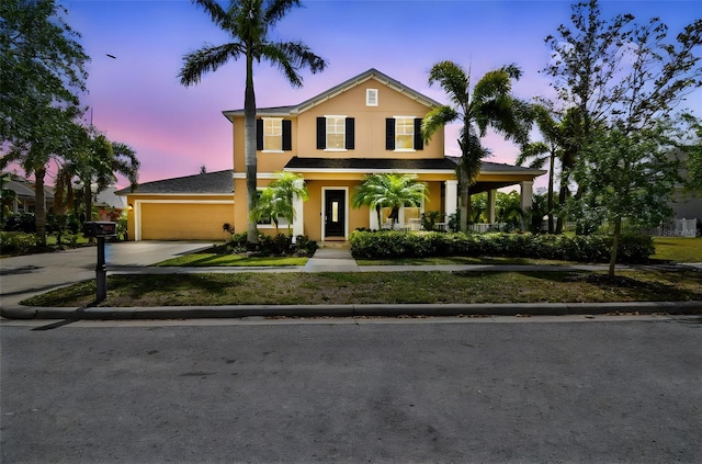 traditional-style house featuring stucco siding, an attached garage, driveway, and a porch