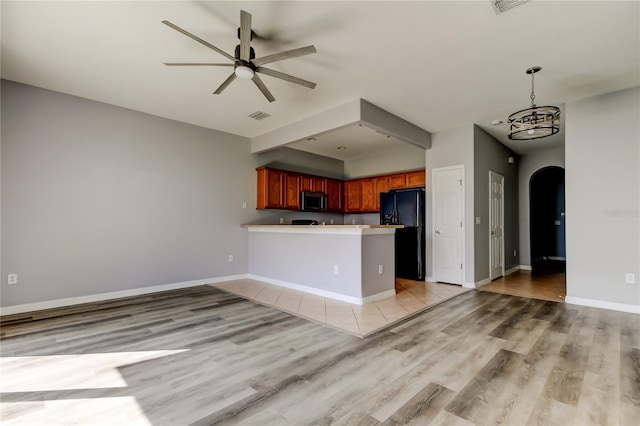 kitchen featuring stainless steel microwave, visible vents, ceiling fan with notable chandelier, a peninsula, and black fridge with ice dispenser