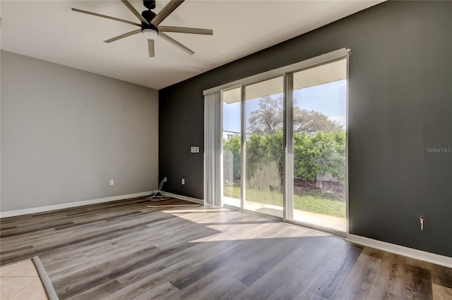 spare room with baseboards, wood finished floors, and a ceiling fan