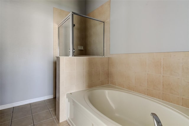 full bath featuring tile patterned floors, a stall shower, baseboards, and a garden tub