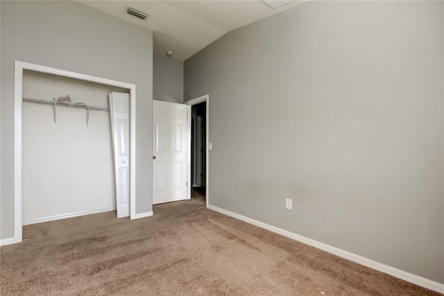 unfurnished bedroom featuring visible vents, a closet, carpet, baseboards, and vaulted ceiling