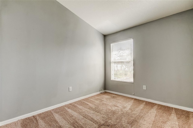 empty room featuring light colored carpet and baseboards