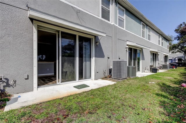 back of house featuring stucco siding, a yard, and central AC unit