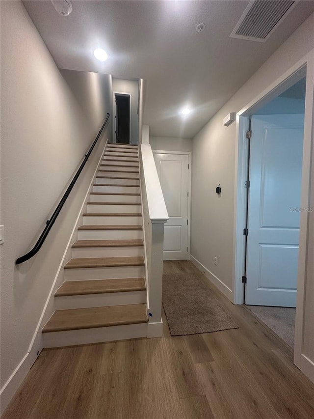 stairs featuring wood finished floors, visible vents, and baseboards