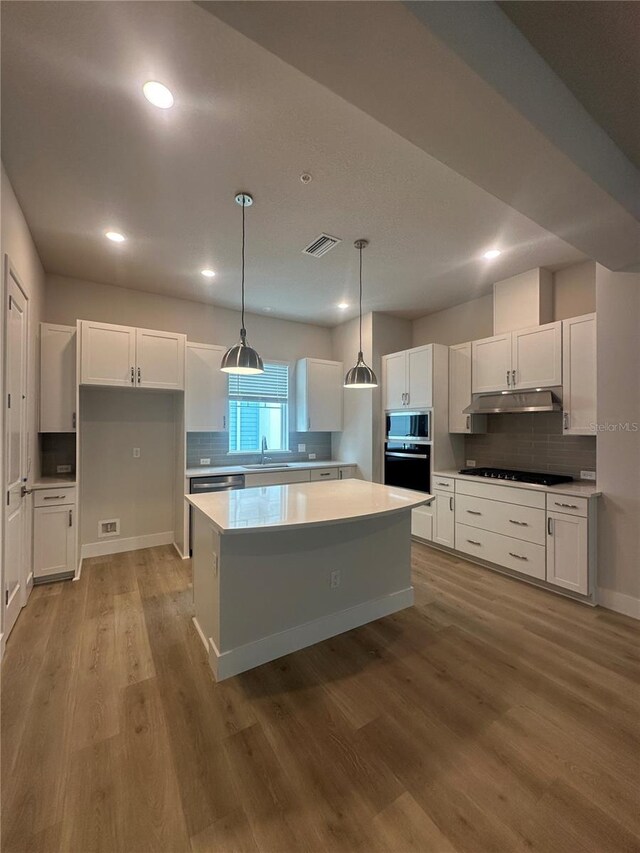 kitchen featuring black appliances, under cabinet range hood, a center island, white cabinets, and light wood finished floors