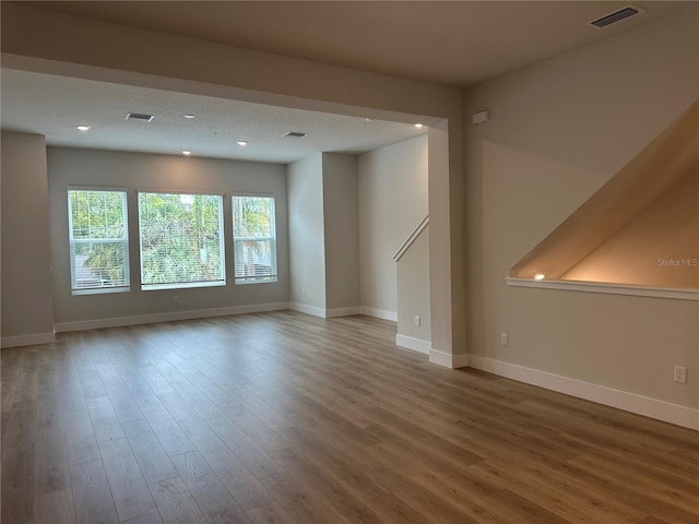 unfurnished living room featuring recessed lighting, wood finished floors, visible vents, and baseboards