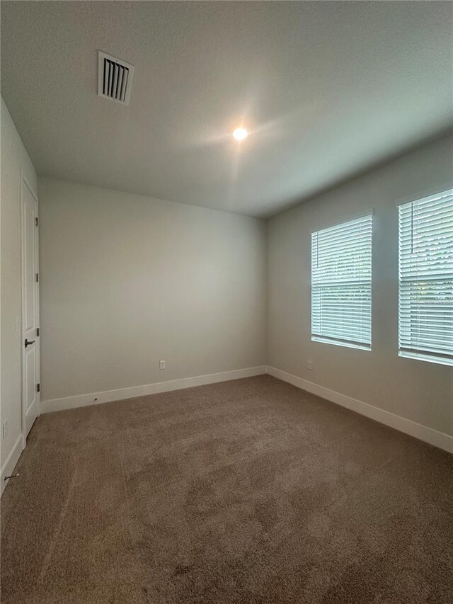 carpeted spare room featuring visible vents, a textured ceiling, and baseboards