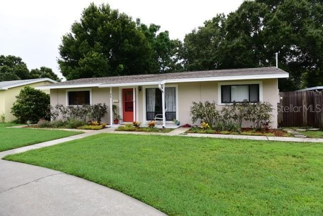 ranch-style home with a front lawn, fence, and stucco siding