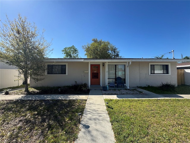 single story home with stucco siding, a front yard, and fence