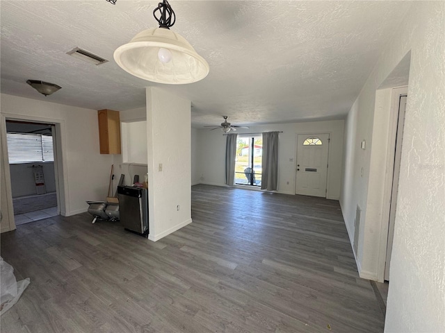 unfurnished living room with ceiling fan, visible vents, a textured ceiling, and wood finished floors