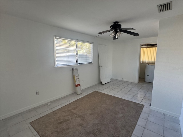 unfurnished room featuring tile patterned floors, visible vents, a ceiling fan, and baseboards