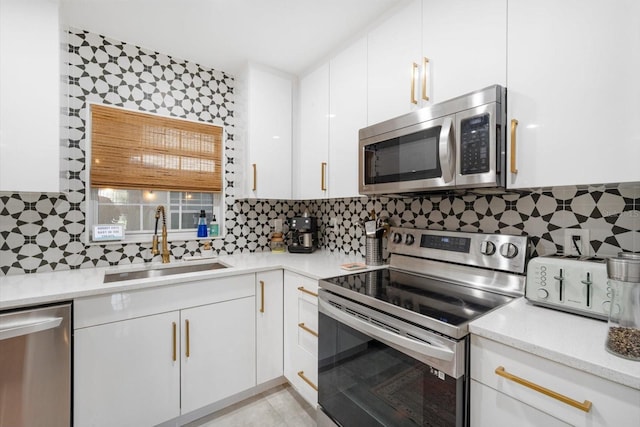 kitchen with a sink, decorative backsplash, white cabinets, and stainless steel appliances