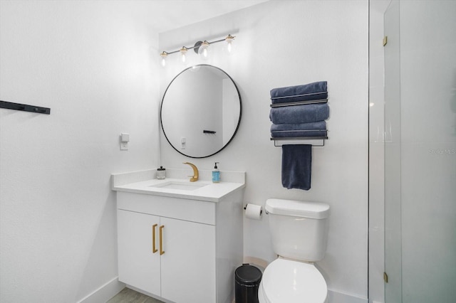 bathroom with toilet, vanity, a shower, and baseboards