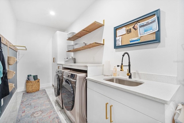 clothes washing area featuring cabinet space, washer and dryer, baseboards, and a sink