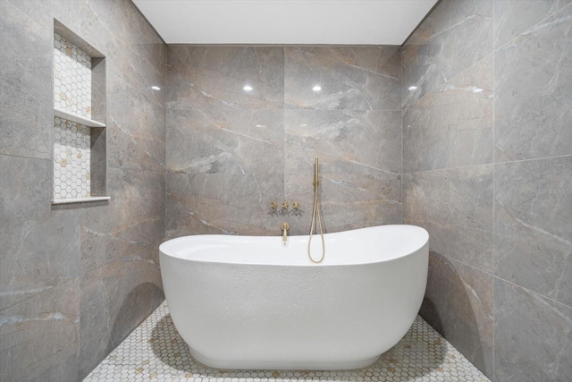 bathroom featuring tile patterned floors, a soaking tub, and tile walls