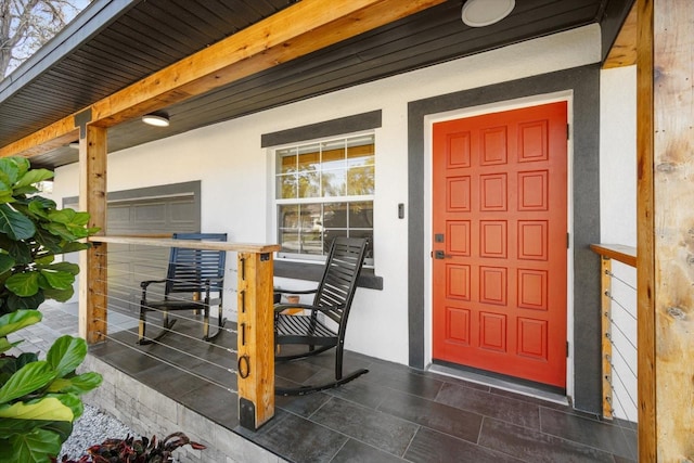 property entrance with covered porch and stucco siding