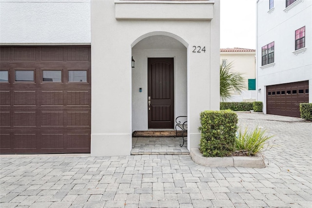 entrance to property with a garage and stucco siding