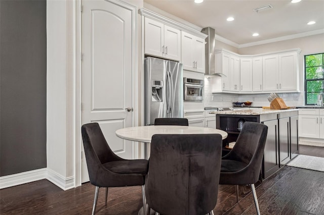 kitchen with appliances with stainless steel finishes, a breakfast bar area, a center island, and wall chimney range hood