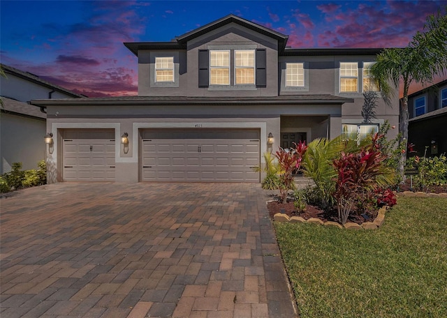 traditional-style house featuring stucco siding, decorative driveway, and a garage