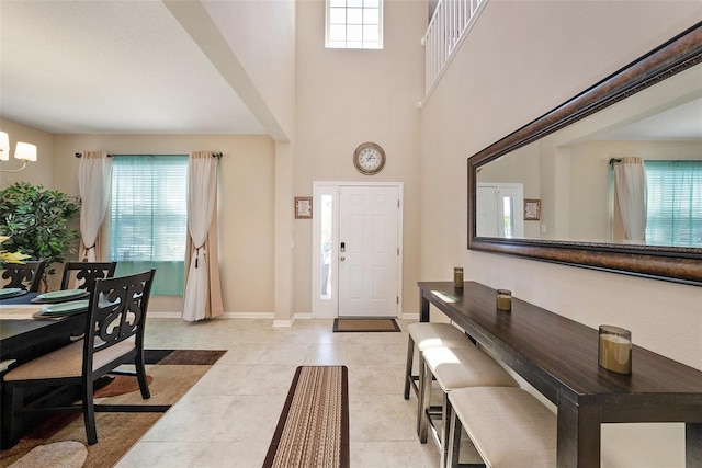 entrance foyer with baseboards, a high ceiling, and light tile patterned flooring