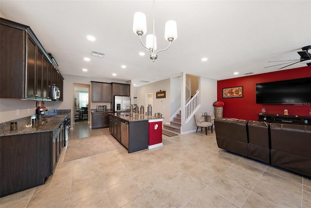 kitchen with a center island with sink, visible vents, stainless steel appliances, dark brown cabinetry, and open floor plan