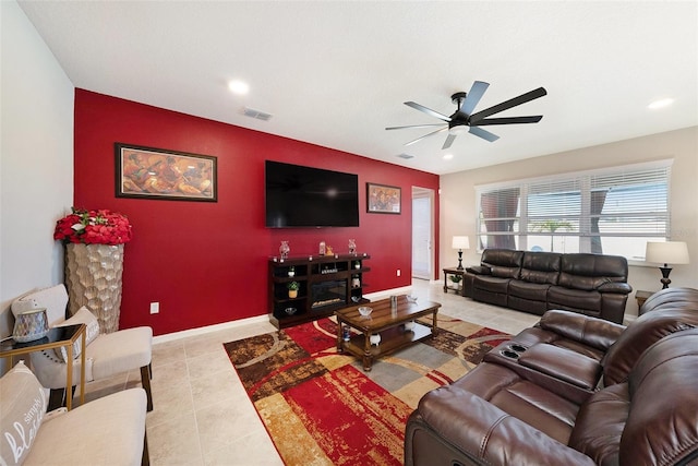 living area with visible vents, an accent wall, baseboards, tile patterned floors, and a ceiling fan