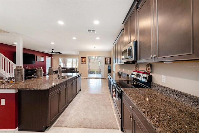 kitchen featuring visible vents, a sink, stainless steel appliances, dark brown cabinetry, and open floor plan