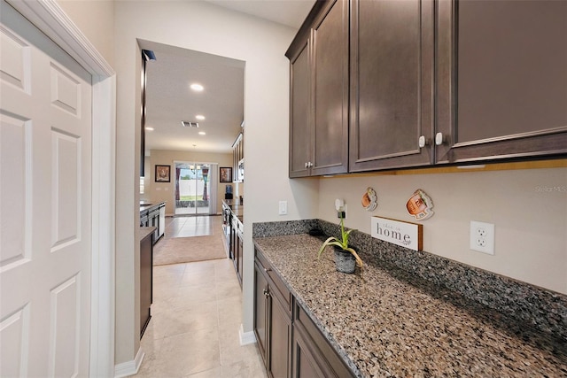 kitchen with visible vents, dark brown cabinets, light tile patterned floors, stone counters, and recessed lighting