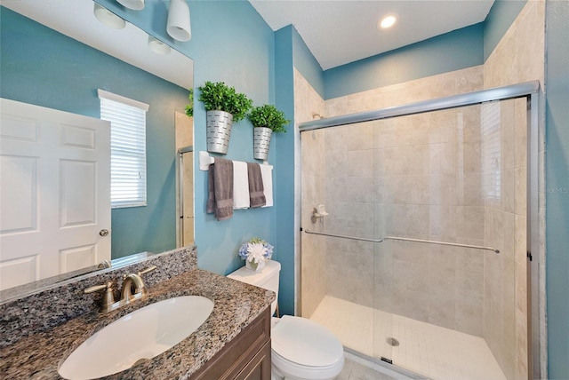 bathroom featuring a stall shower, toilet, and vanity