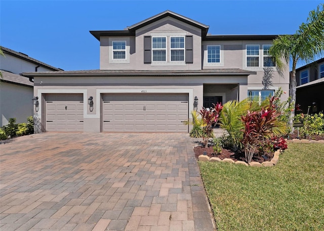 view of front of home featuring decorative driveway, a garage, and stucco siding