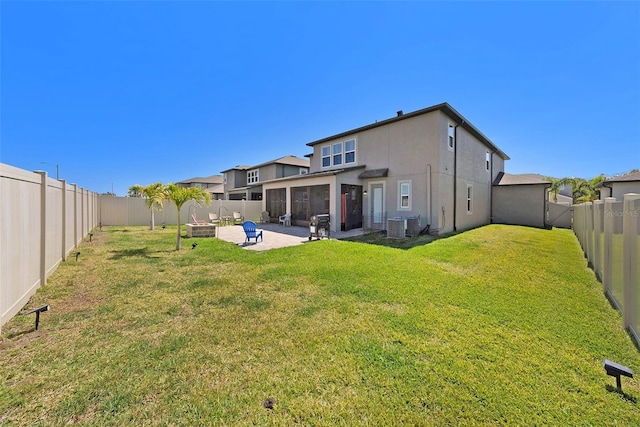 rear view of house featuring stucco siding, a lawn, a fenced backyard, a sunroom, and a patio