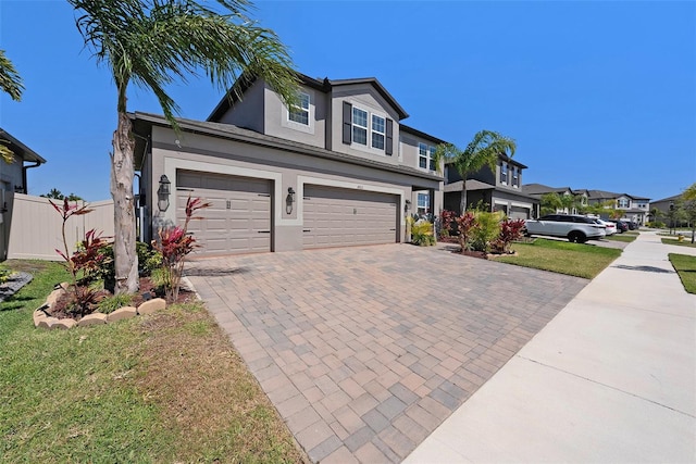 view of front of home with stucco siding, decorative driveway, fence, a front yard, and an attached garage