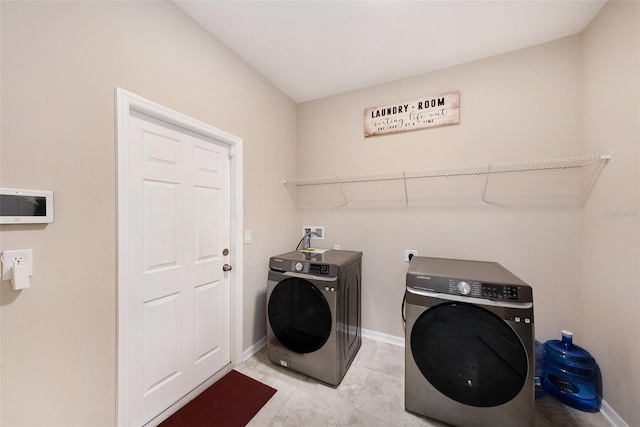 laundry area with laundry area, light tile patterned floors, baseboards, and washer and clothes dryer