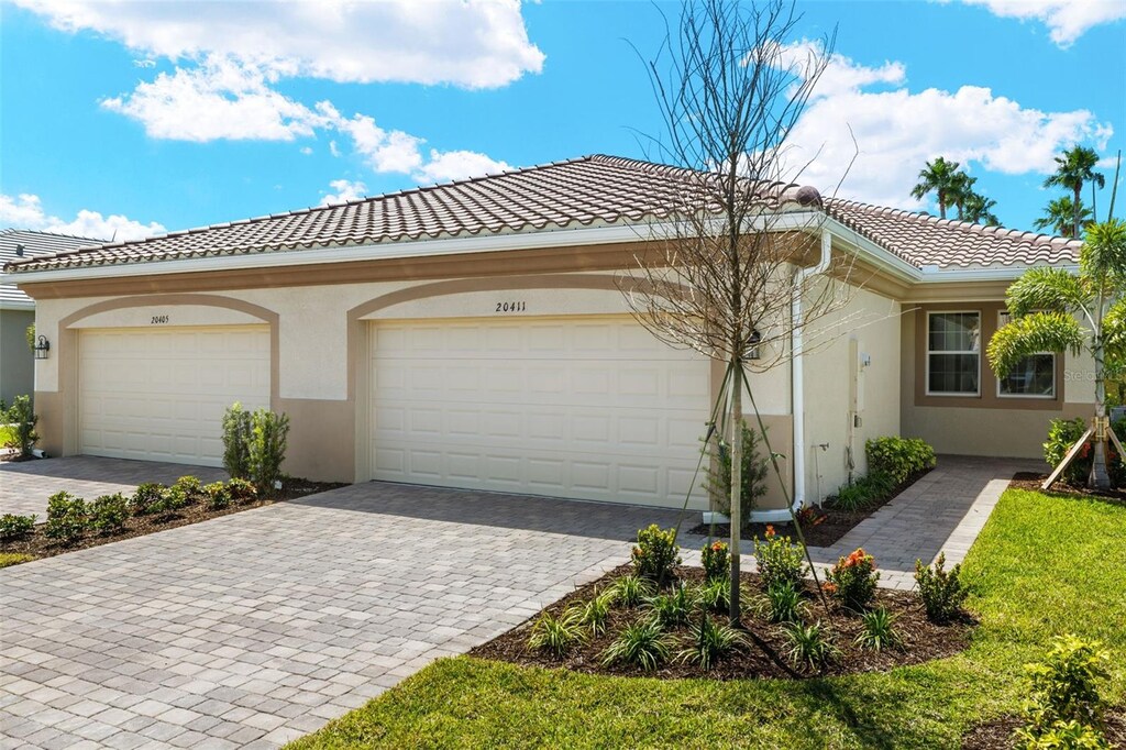 20411 Symphony Pl, Venice, FL 34293 - view of front facade featuring a garage, stucco siding, a tiled roof, and decorative driveway