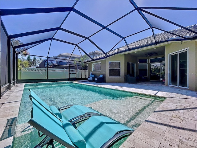 view of swimming pool featuring a ceiling fan, glass enclosure, a patio area, and a fenced in pool